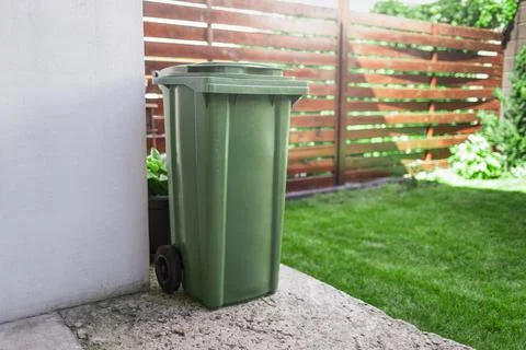 Green large plastic bin for trash on backyard. Stock Photos
