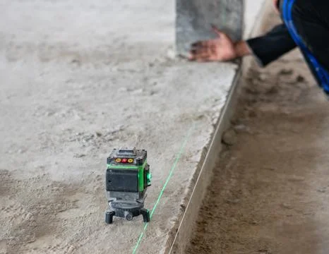 Green laser level tool projecting a precise alignment line on a concrete st.. Fotos Stock