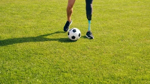 Green lawn with a ball getting kicked by a disabled man Video stock 119090837