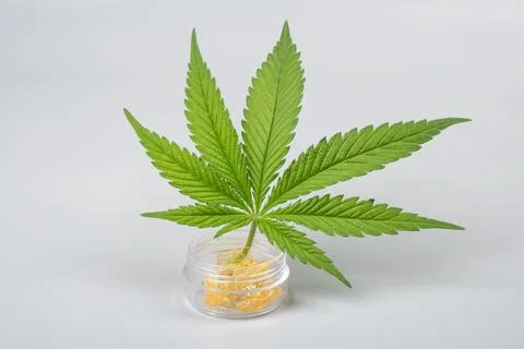 Green leaf and high thc cannabis dab in glass container, extract wax Stock Photos