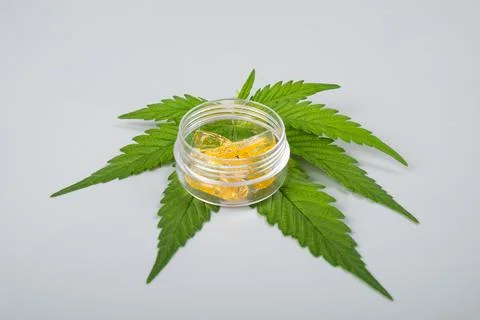Green leaf and high thc cannabis dab in glass container, extract wax Stock Photos