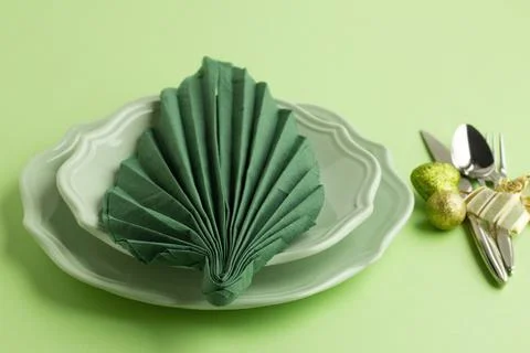 Green leaf-shaped folded christmas napkin on the plate Stock Photos