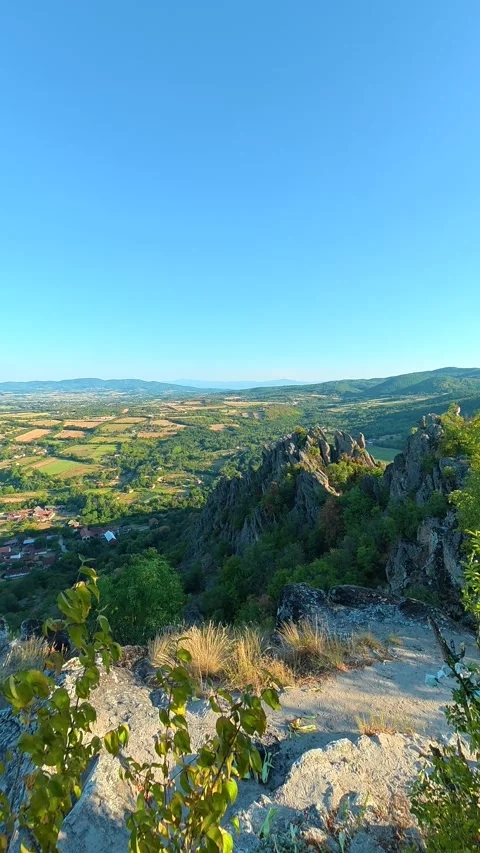 Green leaves frame a vast, sunlit valley. Boracki krs Serbia Vertical 動画素材 345006105