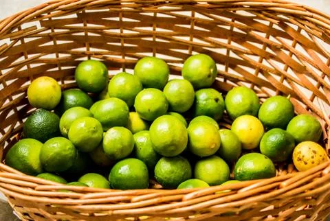 Green lemons in the basket Stock Photos