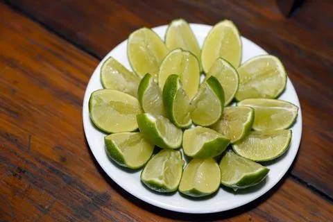 Green lemons cut in bowl Stock Photos