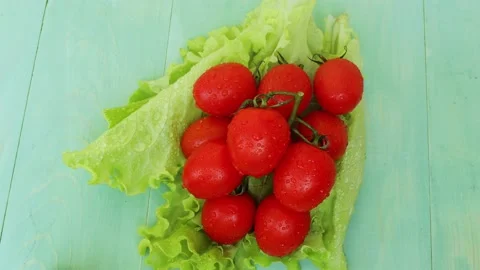 Green lettuce and small red tomatoes. Wooden green background Stock Footage 236542354