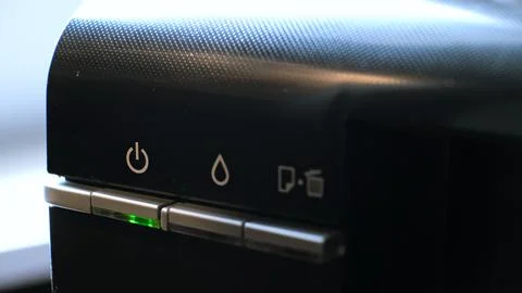The green light on the printer is flashing, indicating of the device or ready to Stock Photos