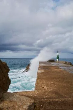 Green lighthouse struck by ocean waves Stock Photos