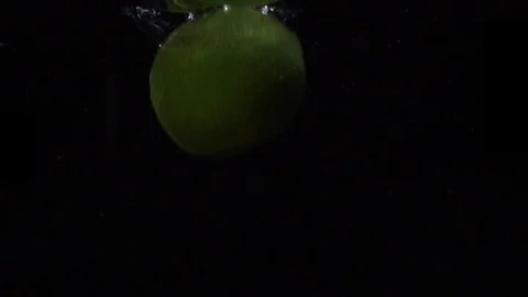 Green lime are thrown into a container of water. Video of fruit in slow motion Stock Footage 105423488