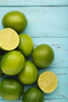 Green lime with cut in half on blue wooden background. Vertical photo Stock Photos