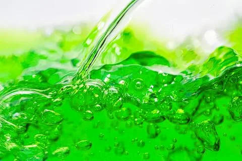 Green liquid being poured with bubbles in a close-up shot Stock Photos