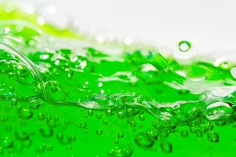 Green liquid with bubbles splashing in a clear container Stock Photos