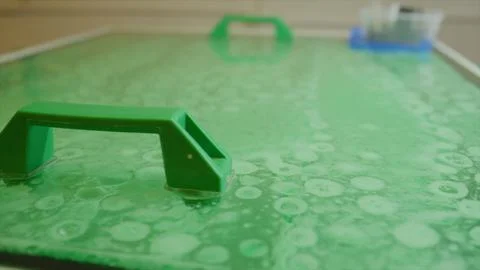 Green liquid with bubbles under transparent surface with handles Stock Photos