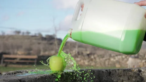 Green liquid falling from a plastic tank on an apple Видео 164148227