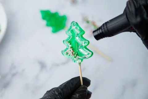 A green lollipop in the form of a Christmas tree is held in the hands of black Stock Photos