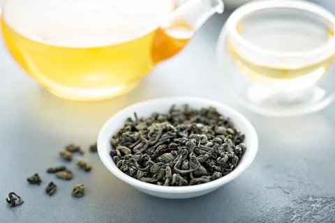 Green loose leaf tea and a teapot Stock Photos