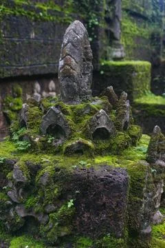 Green lush grass and moss shrouded sculpture of Buddhist pagoda at Wat Tham.. Fotos Stock