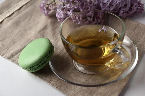 Green macaron and tea on a table with lilac flowers in a cozy setting during 스톡 사진
