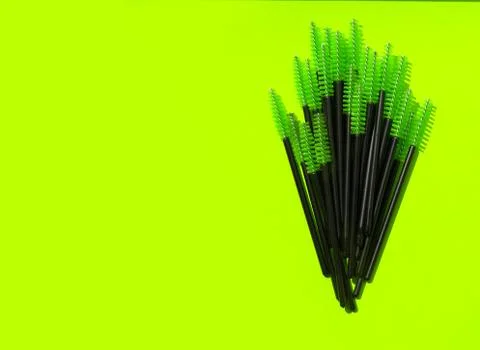 Green makeup brushes, combs for eyelashes and eyebrows on a green background Stock Photos
