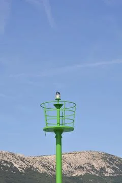 Green maritime navigation light beacon tower against blue sky Stock Photos