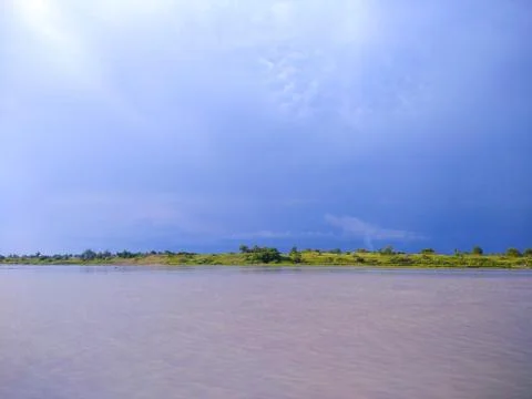 Green meadow by the beach with cloudy clouds behind it Fotos de archivo