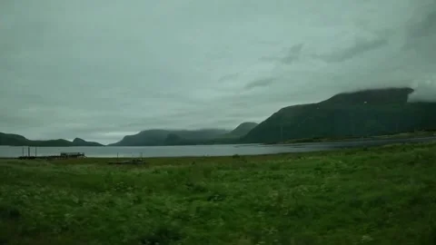 Green meadow small stream and cloud covered fjord mountains in Norway Stock-Footage 341814617