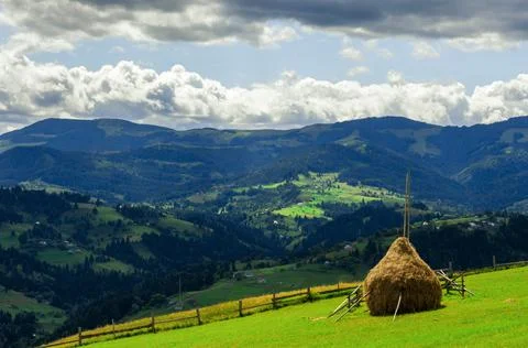 Green meadows in the Carpathian Mountains with a haystack in the foreground Stock Photos