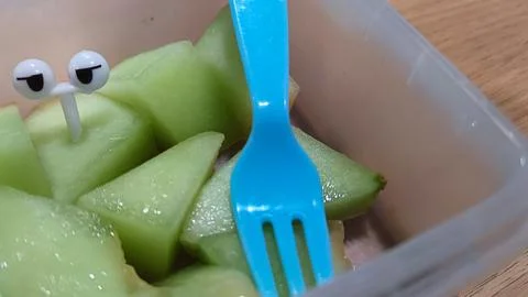 Green melon cut and plastic fork Stock Photos