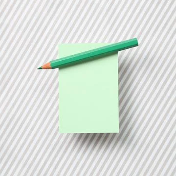 Green memo note pad and green colored pencil on striped pattern fabric Foto stock