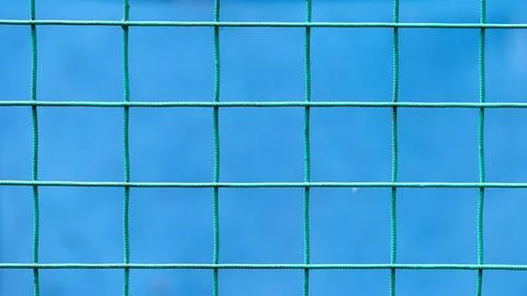 Green metal grid against a solid blue background Stock Photos