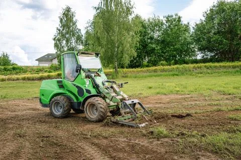A green mini skid steer loader clear the construction site. Land work by the  Stock Photos