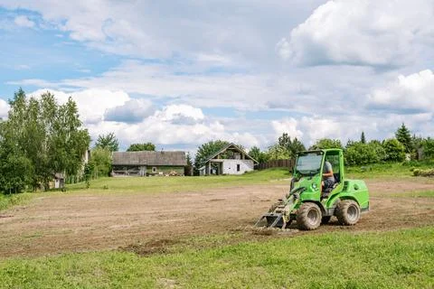 A green mini skid steer loader clear the construction site. Land work by the  Stock Photos