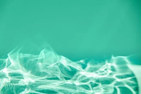 Green mint colored abstract background with light and shadows caustic effect Foto stock