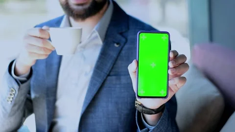 Green mock-up screen on the phone in the arm of an attractive man in a cafe Stock Footage 155378287