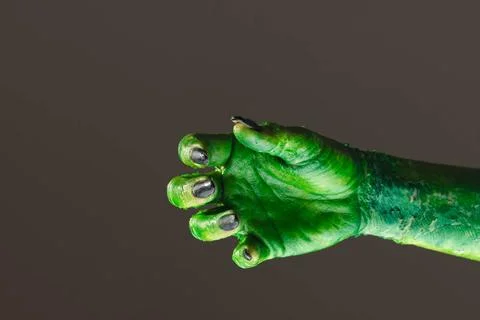  Green monster hand with black nails reaching on grey background. Hallowee... Stock Photos
