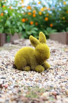 Green Moss Covered Rabbit Statue Decorating Garden of Orange Cosmo Flowers Stock Photos