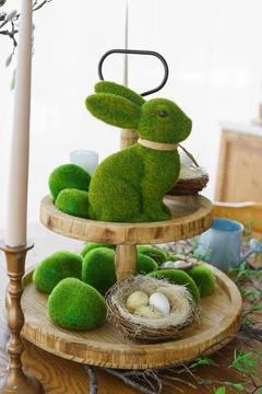 Green moss Easter Bunny and decorative Easter eggs in nest on on two tiered.. Stock Photos