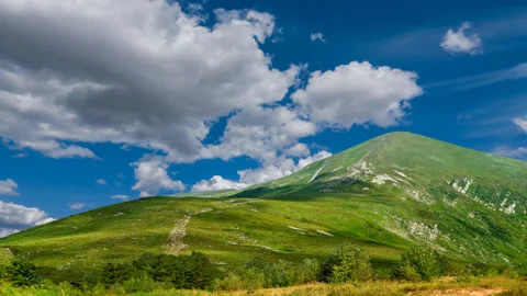 Green mount top under a blue cloudy sky, travel time lapse scene Stock Footage 148838584