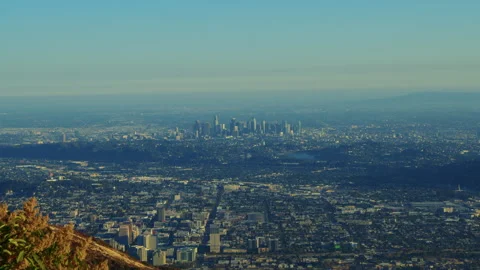 A green mountain in the foreground with the cityscape of Los Angeles in the back Stock Footage 282000602