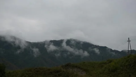 Green mountain slopes covered with thick white clouds in daylight. Video stock 315901716