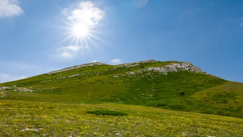 Green mountain under cloudy sky at the sunny day time lapse scene Stock Footage 250153628