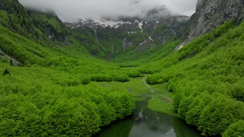 Green mountain valley in spring, clouds above mountains summit Stock Footage 249999678
