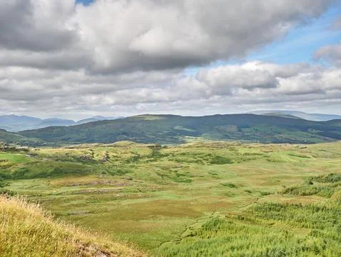 Green mountain valley under dramatic cloudy sky Stock Photos