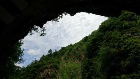 Green mountains and cloud sky seen from the mouth of the cave Stock Footage 243495471