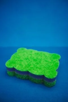 Green multifunctional sponge on a blue background Stock Photos
