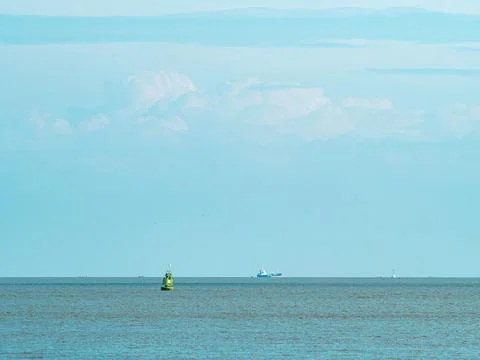 Green navigation buoy floating on open sea with distant cargo tanker ship o.. Stock Photos