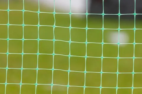 Green netting frames blurred grassy field Stock Photos