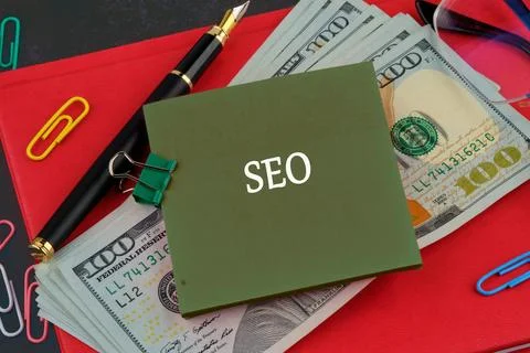 A green notepad marked SEO is placed on top of a stack of hundred dollar bill Stock Photos