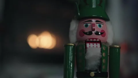 Green nutcracker stands before a cozy glowing fireplace Stock Footage 326707462
