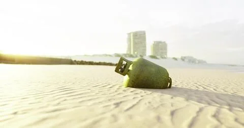 Green object rests on sandy beach near buildings during sunset Ilustración de archivo